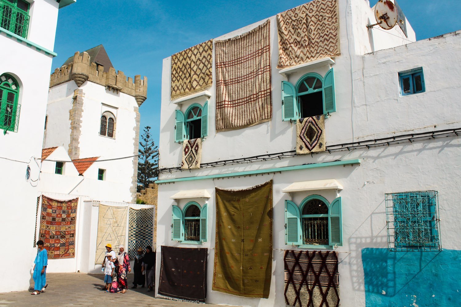 Handwoven carpets hanging from the whitewashed, turquoise-shuttered houses of the Asilah medina