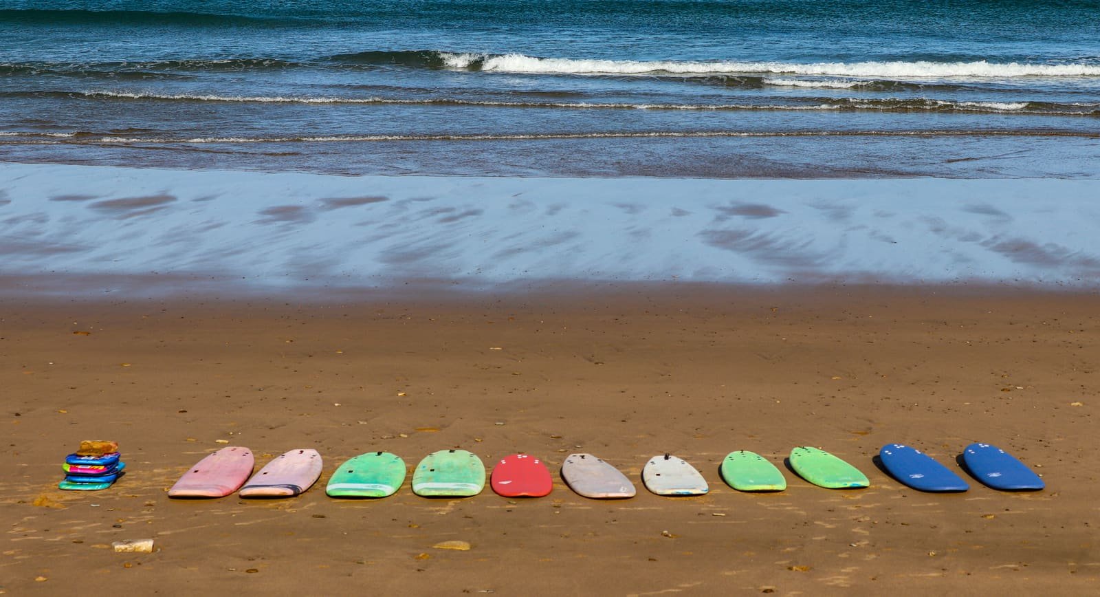 The library surfboards lined up in a row on the sand at Sidi M'Ghait Beach before the party