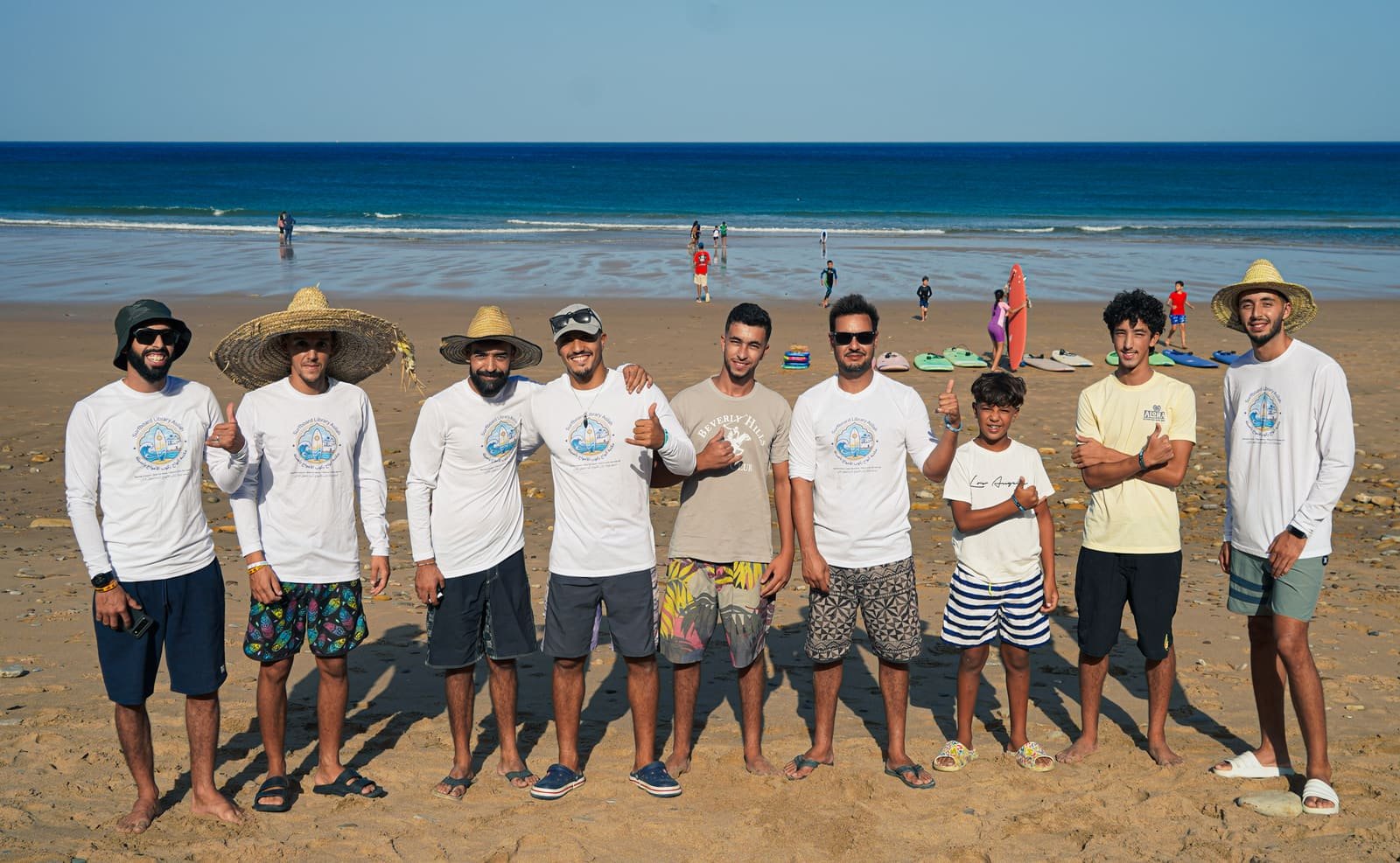 The team of local surf instructors and volunteers standing together on the beach in Surfboard Library shirts