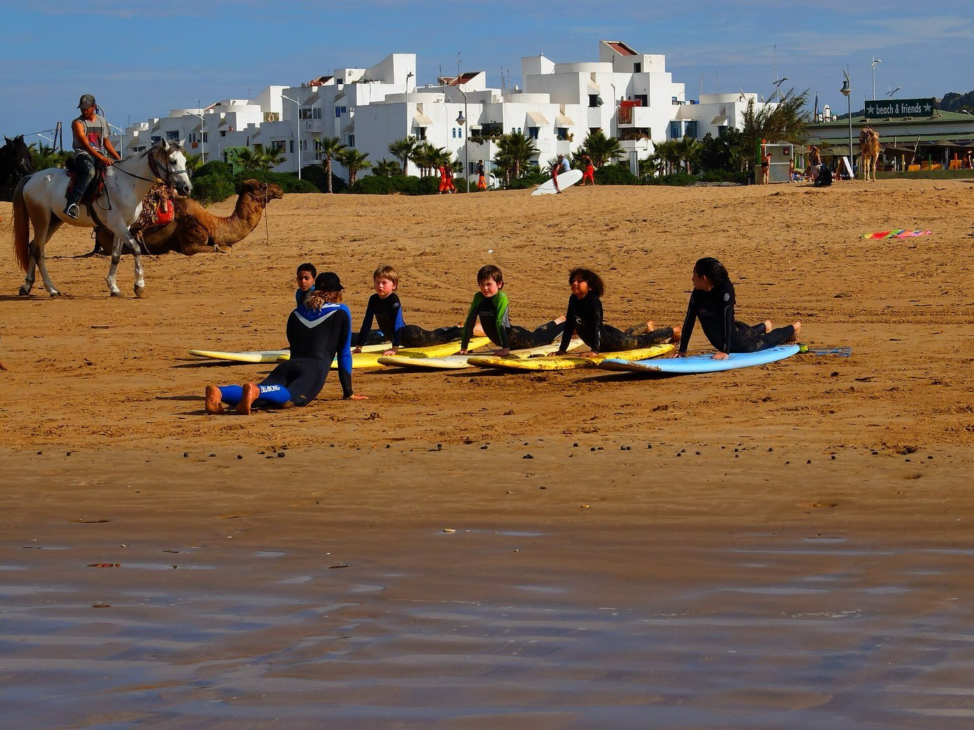 Kids practicing pop-ups on foam surfboards during a surf lesson on a Moroccan beach