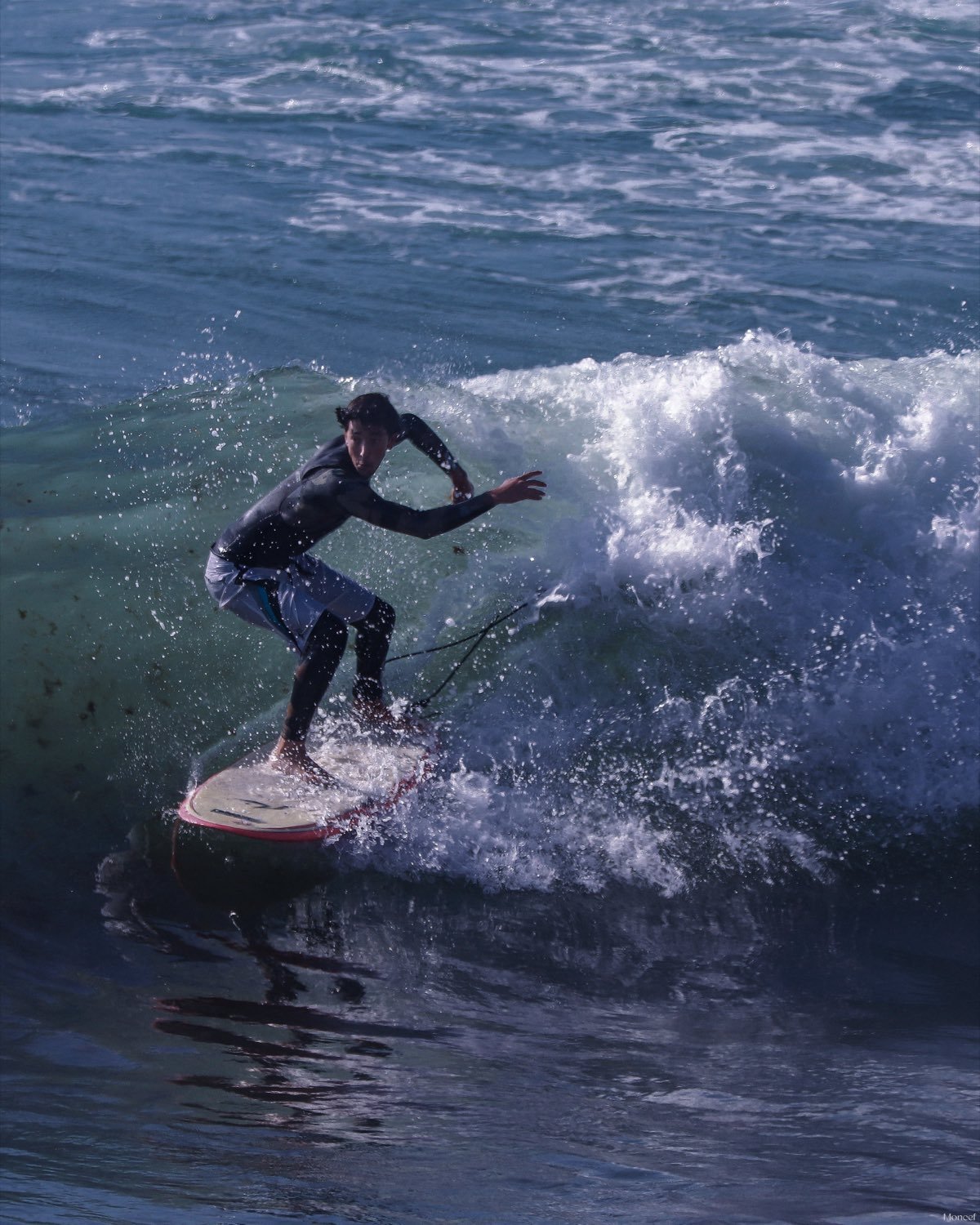 A surfer carving a turn across the face of a clean green wave